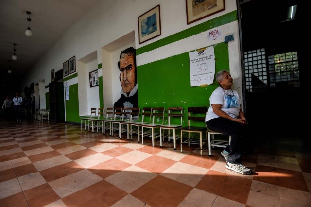 A Venezuelan woman waits at an empty polling station during the presidential elections in Caracas on May 20, 2018 Venezuelans, reeling under a devastating economic crisis, began voting Sunday in an election boycotted by the opposition and condemned by much of the international community but expected to hand deeply unpopular President Nicolas Maduro a new mandate / AFP PHOTO / Juan BARRETO