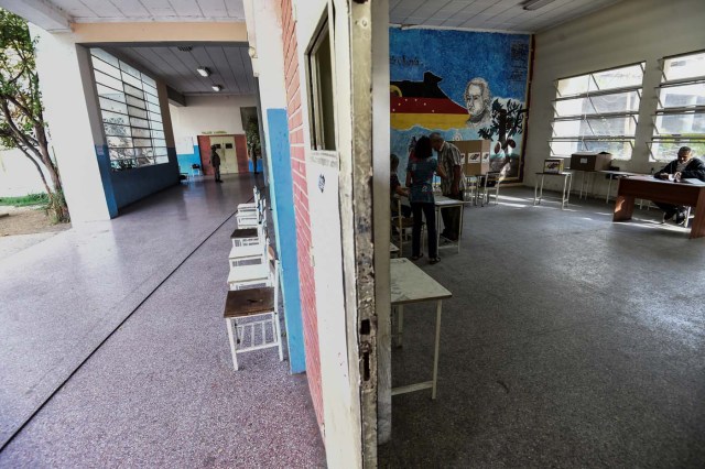A Venezuelan man votes in an empty polling station during the presidential elections in Caracas on May 20, 2018 Venezuelans, reeling under a devastating economic crisis, began voting Sunday in an election boycotted by the opposition and condemned by much of the international community but expected to hand deeply unpopular President Nicolas Maduro a new mandate / AFP PHOTO / Juan BARRETO