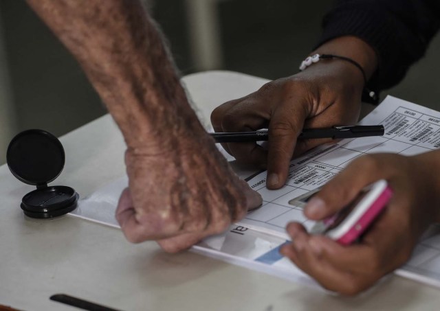 A man casts his vote during the presidential elections at a polling station in Caracas on May 20, 2018 Venezuelans, reeling under a devastating economic crisis, began voting Sunday in an election boycotted by the opposition and condemned by much of the international community but expected to hand deeply unpopular President Nicolas Maduro a new mandate / AFP PHOTO / Juan BARRETO