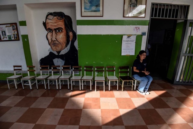 A Venezuelan woman waits at an empty polling station during the presidential elections in Caracas on May 20, 2018 Venezuelans, reeling under a devastating economic crisis, began voting Sunday in an election boycotted by the opposition and condemned by much of the international community but expected to hand deeply unpopular President Nicolas Maduro a new mandate / AFP PHOTO / Juan BARRETO
