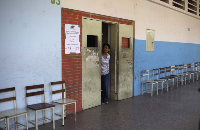 A woman peers out of a door as a polling station stands empty during the presidential election in Caracas, Venezuela, May 20, 2018. REUTERS/Adriana Loureiro