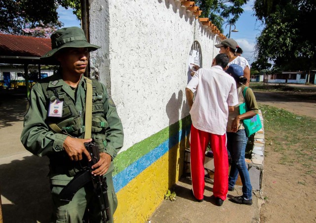 A soldier stands guard as people check electoral lists at a polling station during the presidential election in Puerto Ordaz, Venezuela, May 20, 2018. REUTERS/William R. Urdaneta