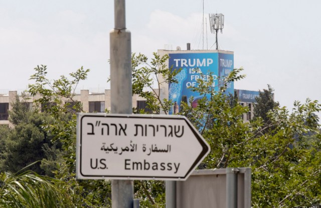 ATS03. JERUSALÉN (ISRAEL), 14/05/2018.- Un cartel en el que se lee "Trump es amigo de Sion", colocado detrás de una señal indica la dirección hacia la Embajada de Estados Unidos, con motivo de su inauguración en Jerusalén, Israel, hoy, 14 de mayo de 2018. La Policía israelí ha desplegado a miles de agentes en Jerusalén para garantizar la seguridad por el polémico traslado hoy de la Embajada de EEUU desde Tel Aviv a la Ciudad Santa, lo que supone un reconocimiento de facto de la capitalidad israelí de la ciudad, en contra del consenso internacional imperante hasta ahora. EFE/ Atef Safadi