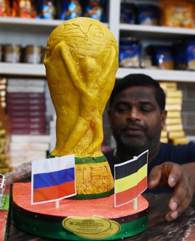 Un trabajador de una confitería organiza la exhibición del modelo de trofeo de la Copa Mundial de la FIFA antes de la próxima Copa Mundial FIFA Rusia 2018, en Calcuta, el 13 de junio de 2018. / AFP PHOTO / Dibyangshu SARKAR