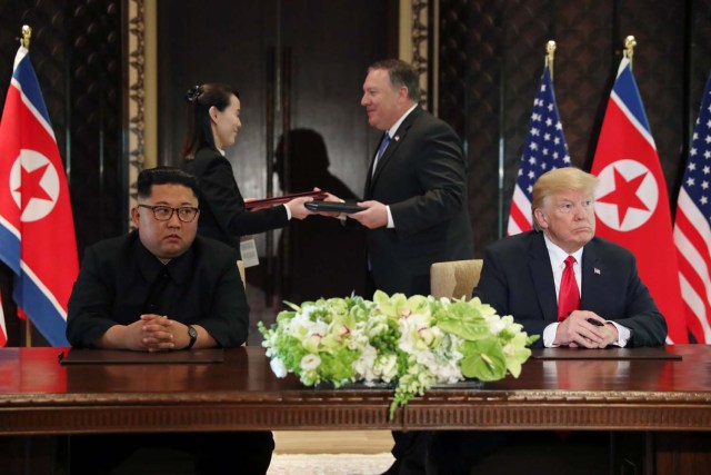 El presidente estadounidense Donald Trump y el líder norcoreano Kim Jong Un observan mientras la hermana de Kim, Kim Yo Jong, intercambia documentos con el secretario de Estado Mike Pompeo en su cumbre en el Hotel Capella en la isla Sentosa en Singapur el 12 de junio de 2018. REUTERS / Jonathan Ernst