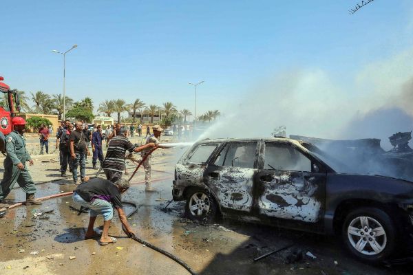Bomberos libios extinguen las llamas, tras el atentado con coche bomba de este sábado en Bengasi. AFP