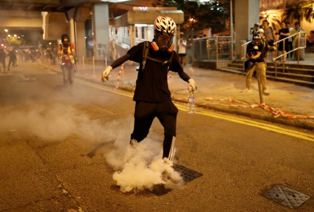 Un manifestante intenta extinguir un bote de gas lacrimógeno mientras los manifestantes contra el proyecto de ley de extradición se manifiestan en el barrio de Kwai Fong en Hong Kong, China, el 11 de agosto de 2019. REUTERS / Issei Kato