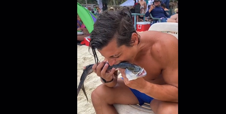 Venezolano paralizó una playa al comerse un pescado CRUDO mientras lo grababa una multitud (Video)